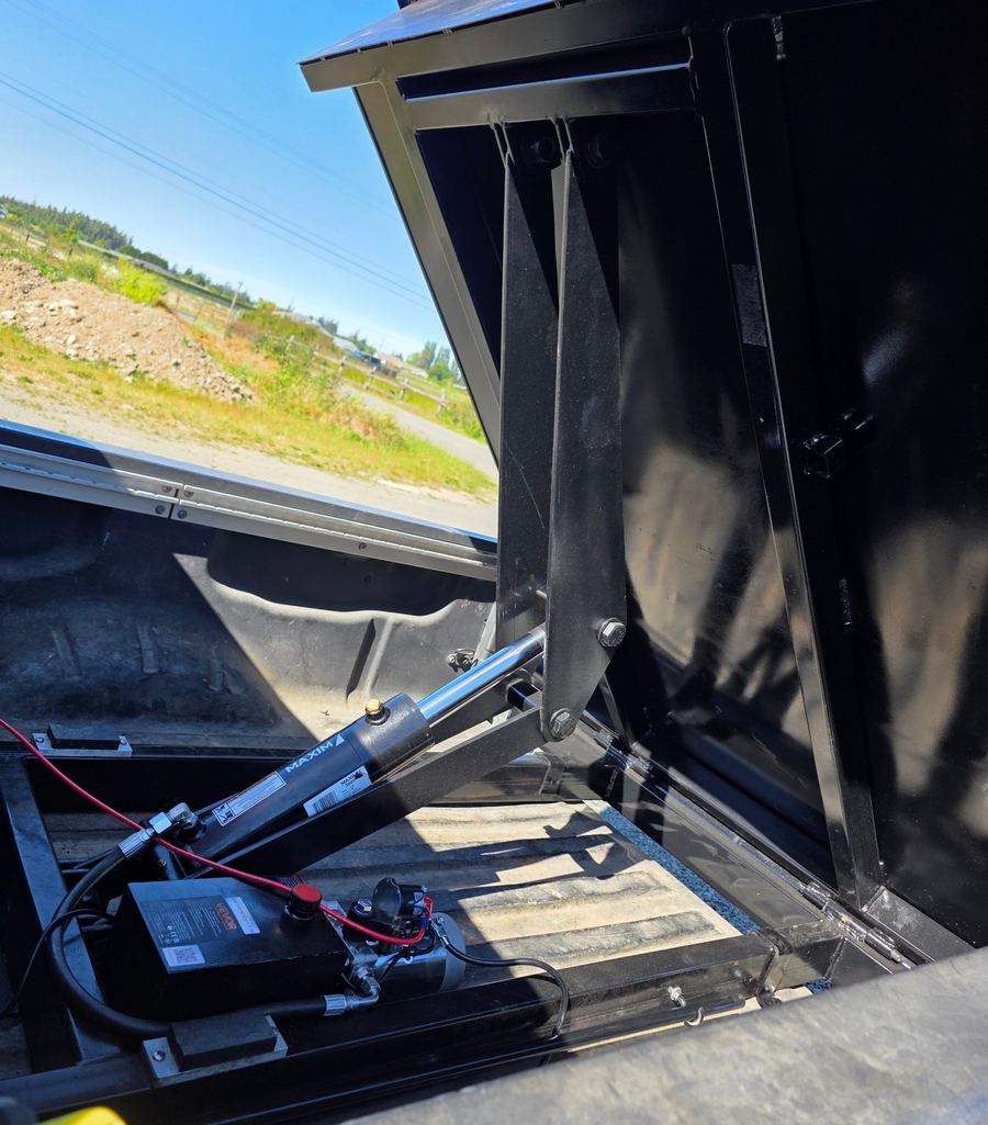 Hydraulic cylinder and steel lift arms under a raised Tilt Titan bed